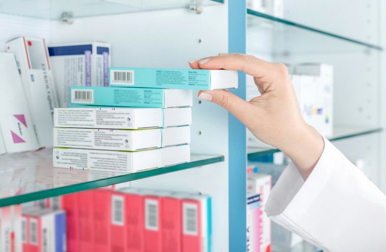 Gyógyszeérsz orvosság dobozát emeli le a polcról